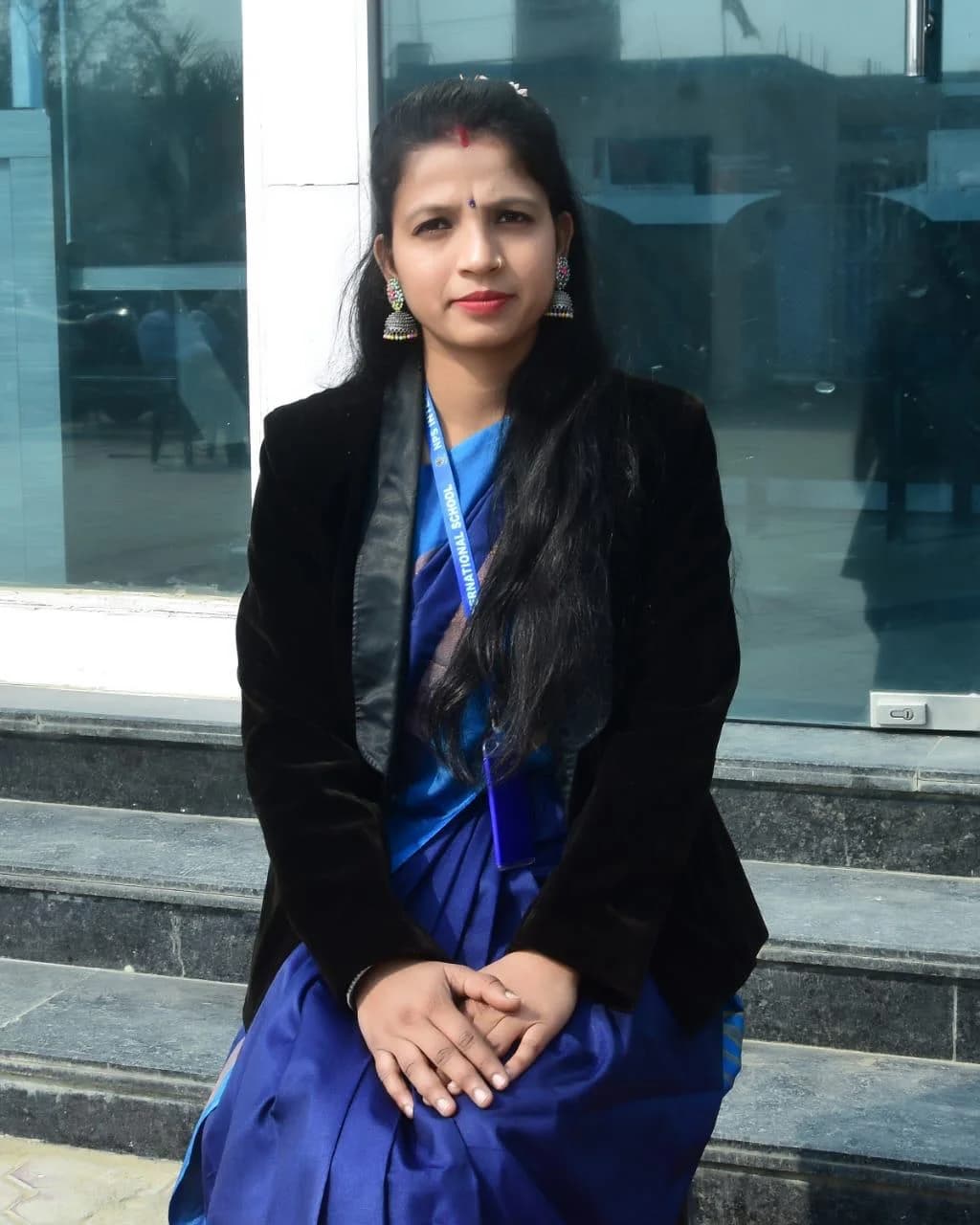 A member of staff seated on the campus steps at NPS International School, Prime City 3 Campus